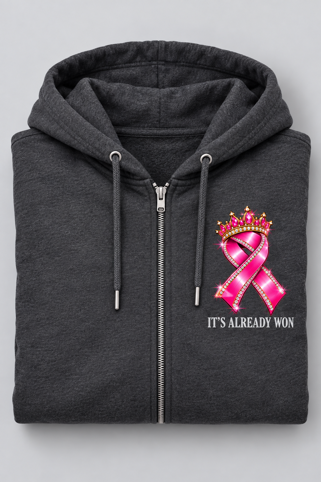 Folded charcoal zip hoodie showing crowned pink ribbon and It's Already Won chest design